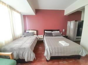 2 camas en un dormitorio con una pared roja en Estudio Moderno! Cerca de la Plaza Principal, en Tarija