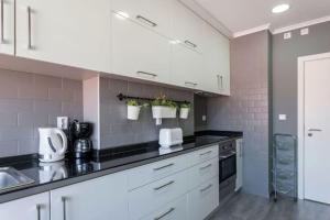 uma cozinha com armários brancos e bancadas pretas em Be Local - Apartment with 2 bedrooms in Moscavide - Lisbon em Lisboa