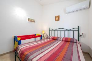 a bedroom with a bed with a colorful striped comforter at Casa vacanze sole e mare in Porto Pino