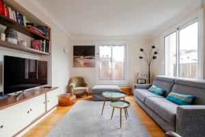 ein Wohnzimmer mit einem Sofa und einem TV in der Unterkunft Veeve - Chaillot Skies in Paris
