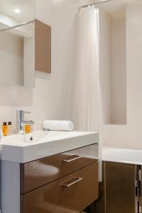 ein weißes Badezimmer mit einem Waschbecken und einer Badewanne in der Unterkunft Veeve - Chaillot Skies in Paris