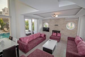 a living room with pink couches and a table at Cihan Villa, Özel Havuzlu, Fethiye in Fethiye