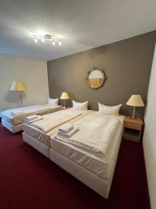 two beds in a room with two lamps and a mirror at Hotel Bonverde (Wannsee-Hof) in Berlin