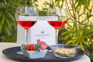 two glasses of wine sitting on a tray with food at Natur Hotel Tanca in Cardedu