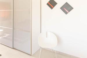 a white chair in a bathroom with glass cabinets at Natur Hotel Tanca in Cardedu