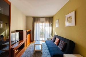 Comfortable 4 rooms 2Bath w balcony في برشلونة: غرفة معيشة بها أريكة زرقاء وتلفزيون