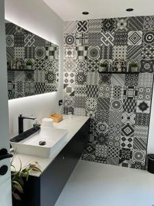 baño con lavabo y pared de mosaico en La maison de Timao en Hannut