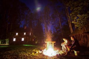 grupa ludzi siedzących w nocy przy ogniu w obiekcie Chatka w lesie 