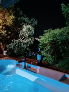 una bottiglia di vino seduta sul bordo della piscina di notte di Glamping el nido a Curití