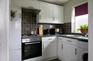 a kitchen with white cabinets and a stove top oven at Cosy tastefully decorated flat in Rainham in Rainham