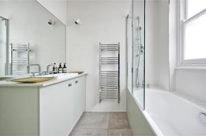 La salle de bains est pourvue d'une baignoire, d'un lavabo et d'une douche. dans l'établissement Veeve - Vividly Vintage, à Londres