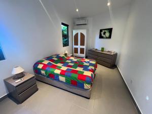 ein Schlafzimmer mit einem farbenfrohen Bett und zwei Nachttischen in der Unterkunft O’ Paradis D’Albion in Albion