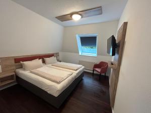 a small bedroom with a bed and a window at Parkhotel Papenburg in Papenburg