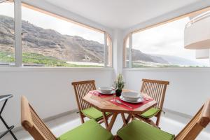 una mesa y sillas en una habitación con ventanas en Apartamento Fabi, en Puerto Naos