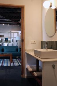 a bathroom with a sink and a mirror and a living room at La Real Urueña in Urueña