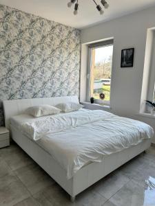 1 cama blanca en un dormitorio con pared en Kawalerka w Górach, en Wałbrzych