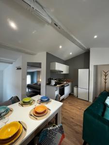 a kitchen and living room with a table with plates on it at La maison castelpontine T4 in Pont-du-Château +23 photos