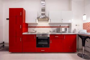 a red kitchen with white cabinets and a stove at Marianna apartment in Budapest