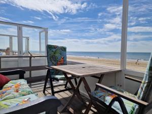 una mesa y sillas en un balcón con vistas a la playa en Slaapstrandhuisje Sleeping Beach House 676 Dishoek aan Zee, en Dishoek