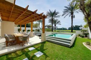 an outdoor patio with a table and a swimming pool at Elara Villas in Dubai