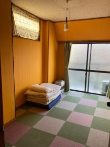 a bedroom with a bed and a checkered floor at 尾道ゲストハウス シータ村 in Onomichi