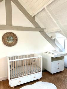 a room with a crib and a ceiling at L'Olivera : entre évasion, sport et nature in Barneville-Carteret