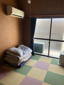 a small room with a bed and a window at 尾道ゲストハウス シータ村 in Onomichi