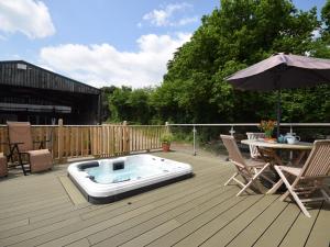 a hot tub sitting on a deck with an umbrella at 2 Bed in Umberleigh 88605 in Chittlehampton