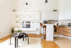 une cuisine avec des placards blancs et une table dans l'établissement Bright Design Riverside Studio by NW, à Budapest