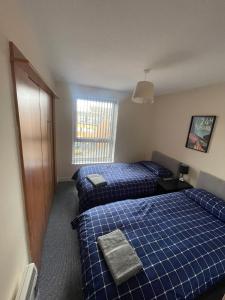 a hotel room with two beds and a window at Ferry Gait Apartments in Edinburgh
