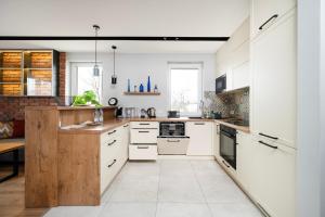 a kitchen with white cabinets and white appliances at Rudzka Góra Comfy Apartment by BookingHost in Łódź
