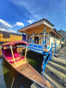 una barca parcheggiata accanto a un molo con un edificio di Pasadona Floating Houseboat a Srinagar