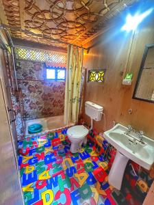 a bathroom with a colorful floor with a toilet and sink at Pasadona Floating Houseboat in Srinagar