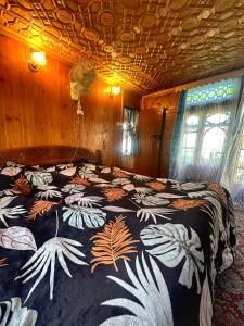 a bedroom with a large bed with a floral blanket at Pasadona Floating Houseboat in Srinagar