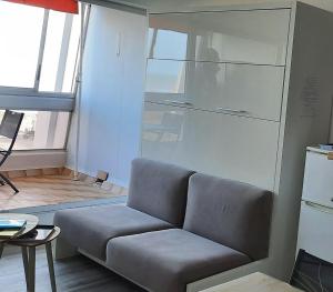 uma sala de estar com um sofá e um frigorífico em Vue superbe sur l'océan, studio et stationnement em Saint-Jean-de-Monts