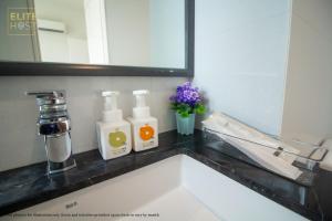 a bathroom sink with two bottles of soap and flowers at PAVILION EMBASSY KLCC By ELITE HOST in Kuala Lumpur