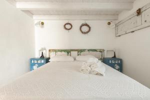 Un dormitorio con una cama blanca con toallas. en Trullo Mandorlo by BarbarHouse, en Carovigno