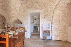 Habitación con pared de piedra, mesa y sillas. en Trullo Mandorlo by BarbarHouse, en Carovigno