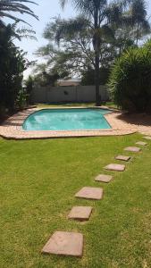 a swimming pool with stepping stones in the grass at Refreshing Space in Eden Glen, Johannesburg, SA in Edenvale