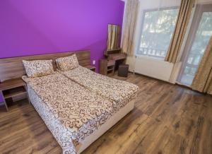 ein Schlafzimmer mit einem Bett und einer lila Wand in der Unterkunft РИБАРНИКЪ in Brŭshlyan