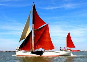 a red and white sail boat in the water at Sailing Barge Reminder in Maldon