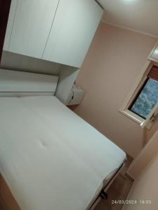 Piccola camera con letto bianco e finestra di Casa dello Stretto a Scilla