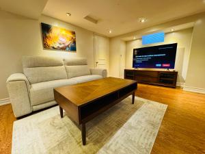 sala de estar con sofá y TV de pantalla plana en Cozy Haven: Modern 2-Bedroom Retreat en Brampton