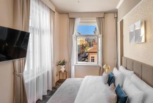 プラハにあるHotel Maestro by Adrezのベッドと大きな窓が備わるホテルルームです。