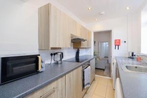 a kitchen with a sink and a microwave at Spacious 4 bed in Coventry City Centre, Sleeps up to 7. in Parkside