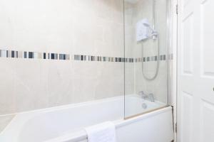 a white bathroom with a tub and a shower at Spacious 4 bed in Coventry City Centre, Sleeps up to 7. in Parkside