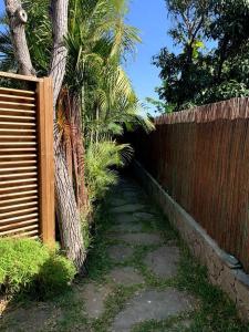 a fence next to a palm tree next to a sidewalk at Ti Cottage sous les Tropiques in Les Avirons