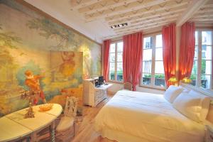 a bedroom with a white bed and a table and windows at Un Bijou à Notre Dame - Heloise in Paris