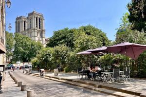 a street with tables and umbrellas and a church at A Gem at Notre Dame in Paris