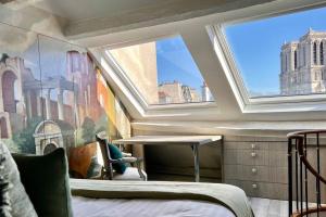 a bedroom with a bed and a table and windows at Rooftop Triplex with Garden at Notre Dame in Paris